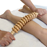 Person using a wooden massage roller on their leg